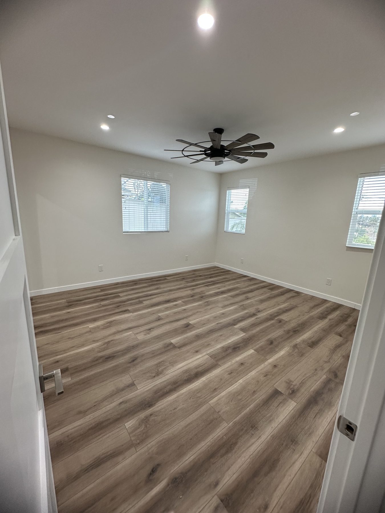 Bright bedroom with three windows and ceiling fan at 1148 S Rimpau Blvd