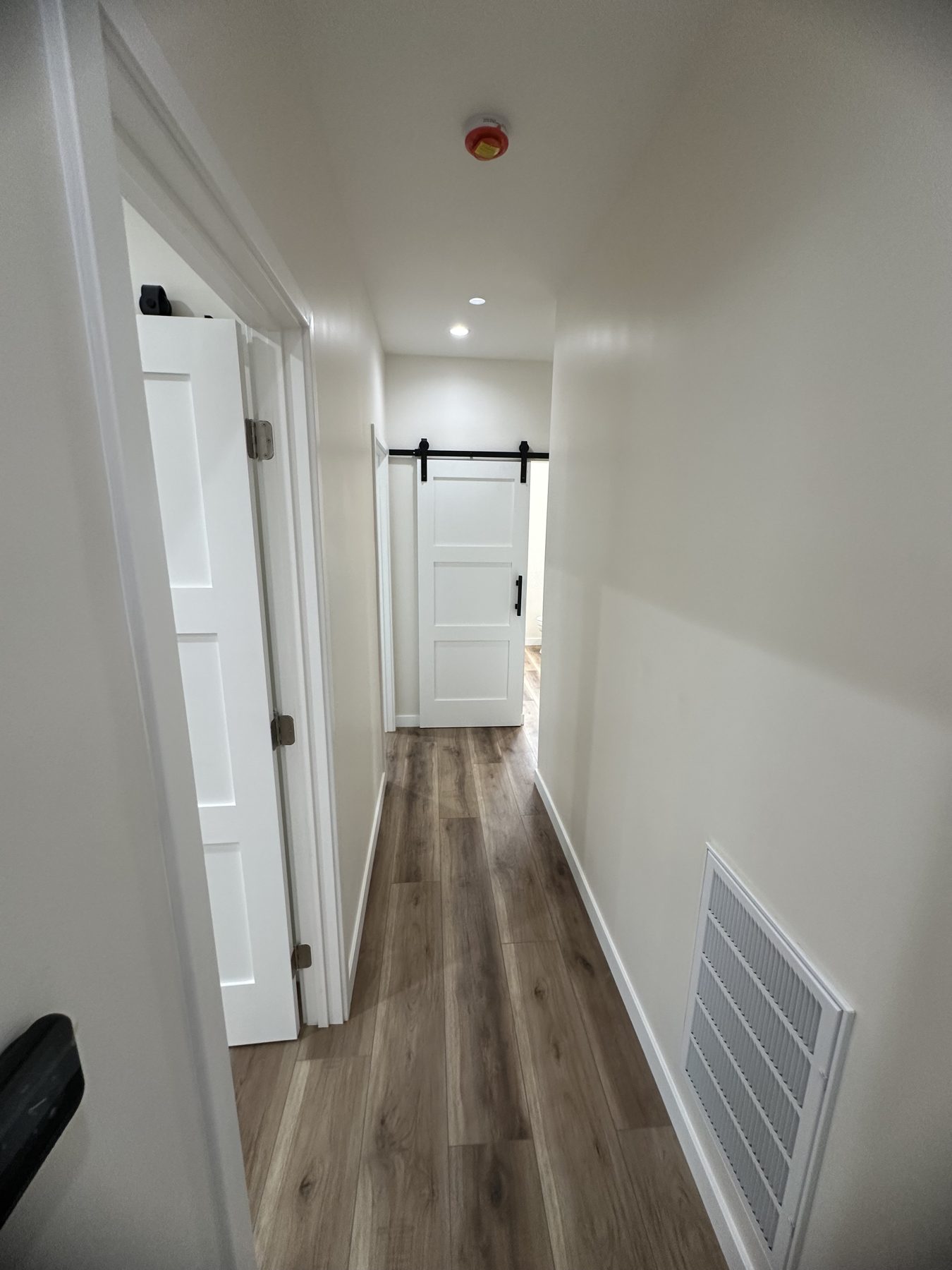 Hallway with recessed lighting leading to a barn-door bathroom at 1148 S Rimpau Blvd