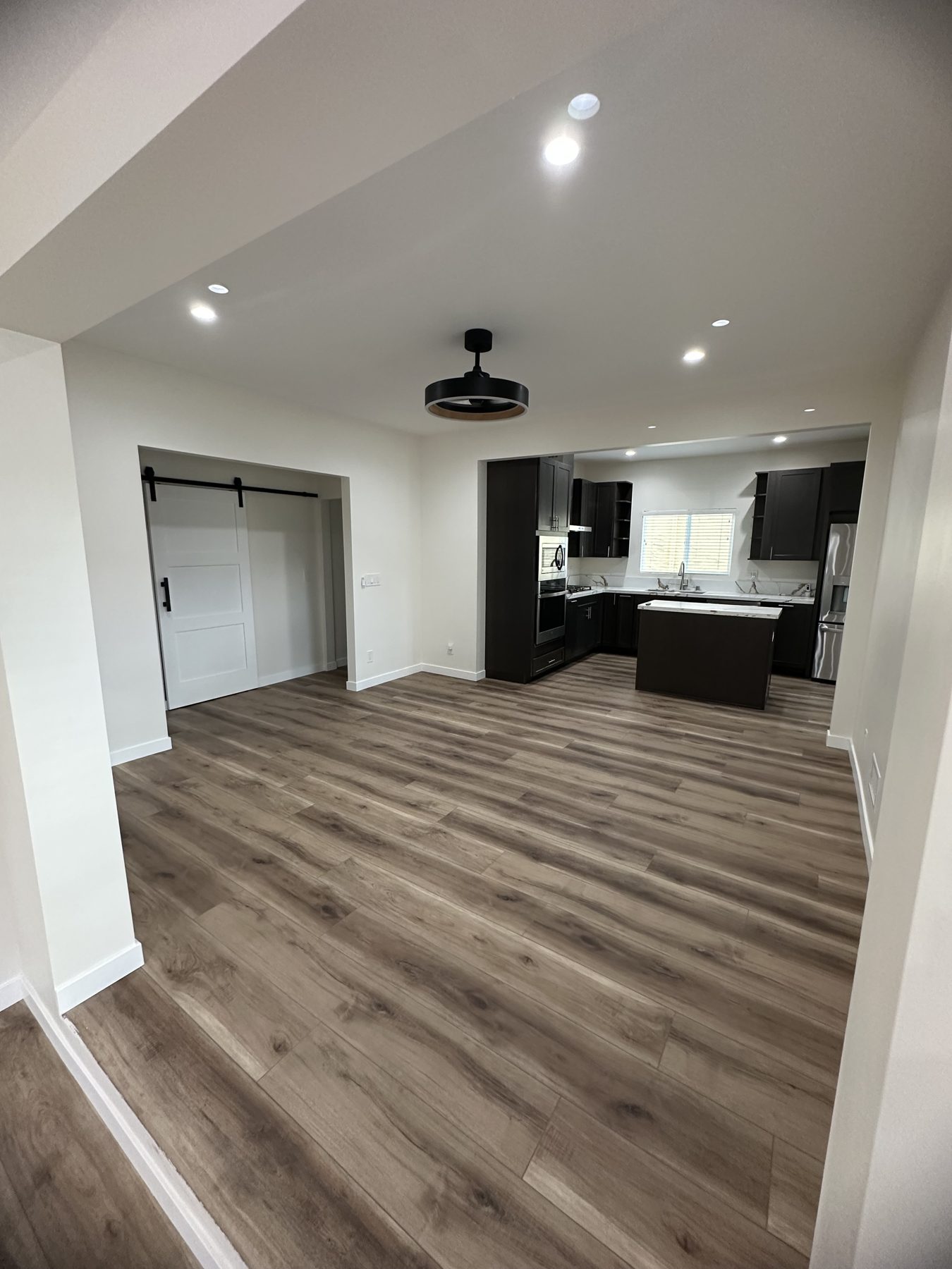Open dining area flowing into the kitchen, with ceiling fan and barn door at 1148 S Rimpau Blvd